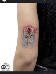 a woman's arm with a watercolor rose tattoo on the left inner arm