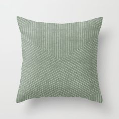 a green pillow on a white wall with a black and white striped design in the middle