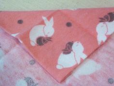 a pink and white dog bandana laying on top of a bed