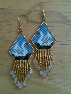 a pair of earrings with beaded fringes on top of a wooden table next to a