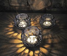 three lit candles sitting on top of a table next to newspaper pages and an open book