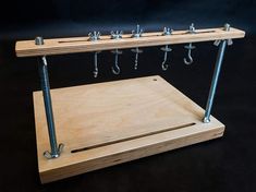 a wooden shelf with hooks and screws attached to the top on a black background