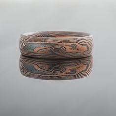 "This rustic 6mm Mokume Gane band is shown in the Woodgrain Pattern and the Flame metal combination. The Flame palette features 14k red gold and sterling silver. Mokume Gane Band Width: 6mm Palette: Flame Pattern: Woodgrain Finish: Etched + Oxidized Profile: Low Dome Price does NOT include stones or setting fees. We care about customer service and would like to hear from you! Please contact us to help create your treasured item, we take your concerns and requests to heart and will work together Mokume Gane Ring, Woodgrain Pattern, Titanium Wedding Rings, Mokume Gane, Custom Wedding Rings, Silver Gemstone Jewelry, Wedding Rings Vintage, Small Rings, Black Box