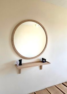 a round mirror mounted on the wall above a shelf