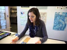 a woman sitting at a table with some art supplies