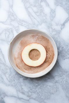 an apple is in a bowl on a marble counter top with powdered sugar and cinnamon