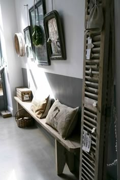 a wooden bench sitting in the middle of a room next to a wall with pictures on it