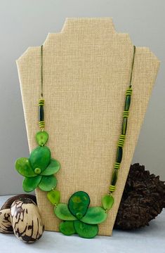 Handmade in Ecuador Necklace Length: 28 Inches Material: Tagua Nut Gold Handmade Clasp Due to this item being handmade and the nature of the Tagua Nut the size and the color may vary from piece to piece Artisan Green Jewelry With Wooden Beads, Green Wooden Beads Jewelry For Gift, Green Wooden Beads Jewelry Gift, Handmade Green Bohemian Flower Necklace, Nature-inspired Green Beaded Necklaces For Gift, Nature-inspired Green Beaded Necklaces As Gifts, Nature-inspired Green Jewelry With Wooden Beads, Green Long Necklace For Beach, Green Bohemian Flower Necklace