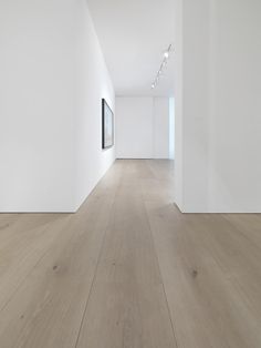 an empty room with white walls and wood flooring is seen in this image, there are two framed pictures on the wall