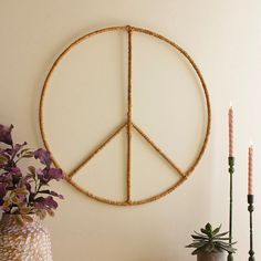 a peace sign made out of bamboo sticks on a wall next to flowers and candles