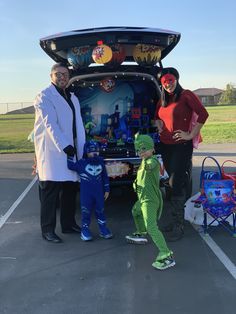 three people standing in front of a vehicle with the trunk open and two children dressed as characters