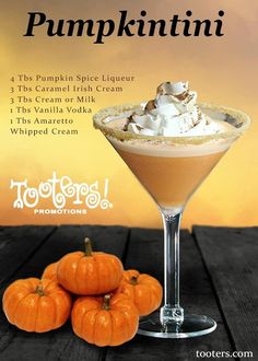 the pumpkin spice liqueur is served in a martini glass with whipped cream and mini pumpkins