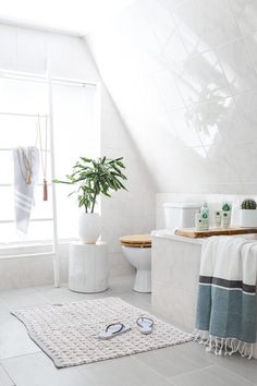 a bathroom with white walls and tile flooring, a potted plant in the corner