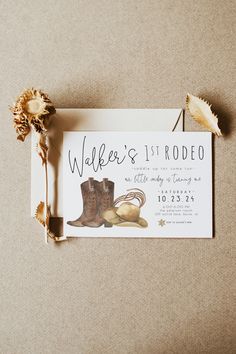 an image of a wedding card with boots and flowers on the table next to it