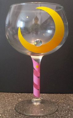 a clear wine glass with yellow and pink designs on the rim, sitting on a counter