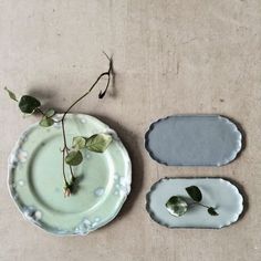 three plates with flowers on them sitting next to each other in front of a wall