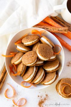 a bowl filled with cookies and carrots next to some cinnamon sticks on a table