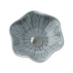 a ring sits in the middle of a flower shaped bowl with a pearl bead on it