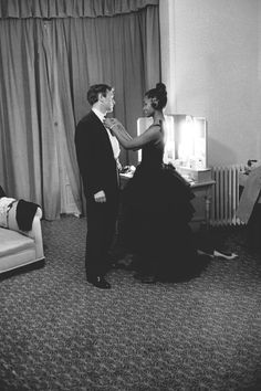 a man in a tuxedo helping a woman with her dress