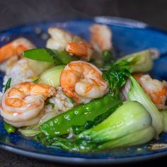 a blue plate topped with shrimp, broccoli and rice