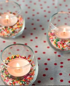 three small glass vases filled with candles and sprinkles on a table