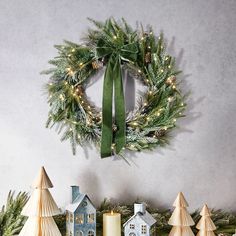 a wreath on the wall with christmas decorations around it and lit candles in front of them