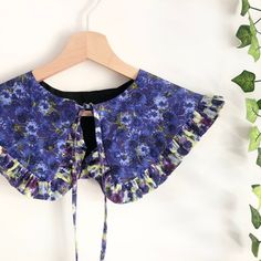 a purple flowered blouse hanging on a wooden hanger