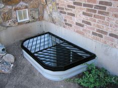 an air vent on the ground next to a brick wall