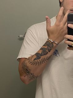 a man taking a selfie in the mirror with his cell phone and tattoos on his arm