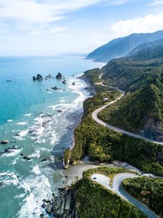 an aerial view of the ocean and coastline with cars driving on it's road