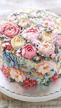 a close up of a cake on a plate with many different colors and flowers around it