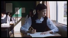 a woman sitting at a desk writing on a piece of paper