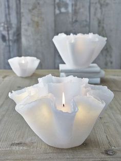 two white vases sitting on top of a wooden table next to eachother