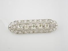 Vintage platinum diamond brooch. The brooch features five European and twenty-eight full cut diamonds. The diamonds weigh approximately 3.50 carats total and have F-H color and VS2-SI2 clarity. The brooch measures 2 inches by 9/16 inches and weighs 6.07dwt. The brooch features an openwork design with filigree and milgrain detailing. Classic Platinum Brooch With Brilliant Cut, Classic Diamond Brilliant Cut Brooch, Classic Diamond White Diamond Brooch, Classic Diamond Brooch With Brilliant Cut, Classic Brilliant Cut Brooch For Anniversary, Classic Diamond White Brooch For Anniversary, Classic Brilliant Cut Brooches For Anniversary, Classic Diamond Brooches With Brilliant Cut, Classic White Diamond Brooches