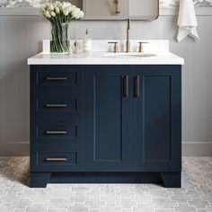 a bathroom vanity with blue cabinets and white flowers in the vase next to the mirror