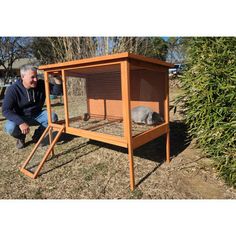 a man kneeling down next to a small animal cage