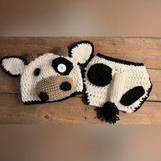 two crocheted cow hats on top of a wooden table