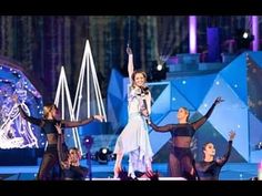 a group of dancers on stage with their arms in the air and one woman holding her hands up