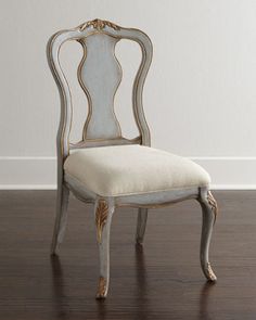 an antique chair with white upholstered back and gold trimmings on the seat