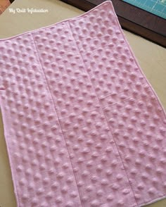 a pink piece of cloth sitting on top of a wooden table next to a ruler