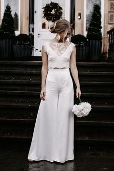 a woman in white is standing on the steps with her wedding bouquet and dress up