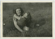 an old black and white photo of two women laying in the grass