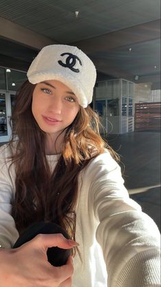 a woman in a white hat is holding something up to the camera with her right hand