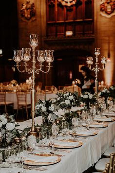 a long table is set with white flowers and candles