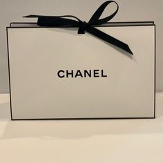 a white box with a black ribbon tied around the lid that says, chanel