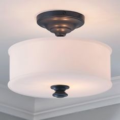 a ceiling light with a white shade on it's side and a black fixture in the middle