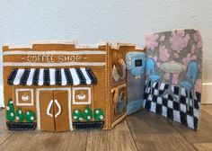 two small cardboard houses made to look like they are in the shape of coffee shops