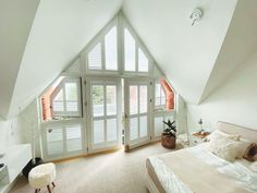 an attic bedroom with white walls and windows