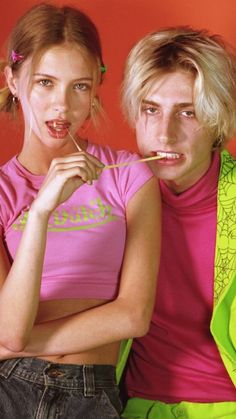 two young people posing for a photo with toothbrushes in their mouth and one holding something up to her mouth