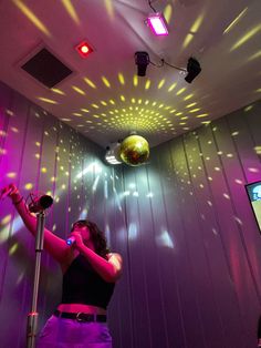 a woman standing next to a microphone in a room with lights on the walls and ceiling